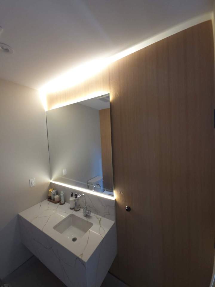 Salle de bain avec lavabo en marbre miroir lumineux et mur en bois clair Laval