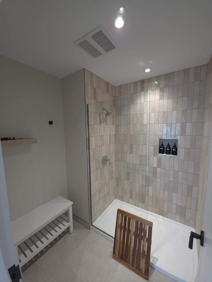 Douche moderne avec carrelage clair banc et caillebotis en bois Laval